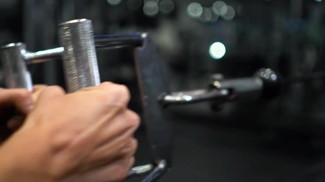 An athlete is using the lateral row machine at a gym. CLOSE UP shot at 120 frames per second of the handlebar.