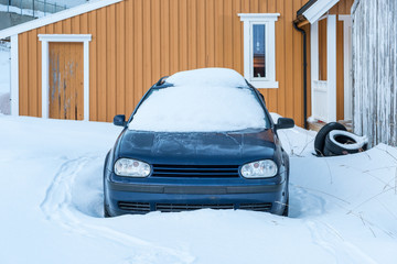 Car under the snow on front house