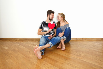 Happy young couple in love sitting on the floor in their apartment.