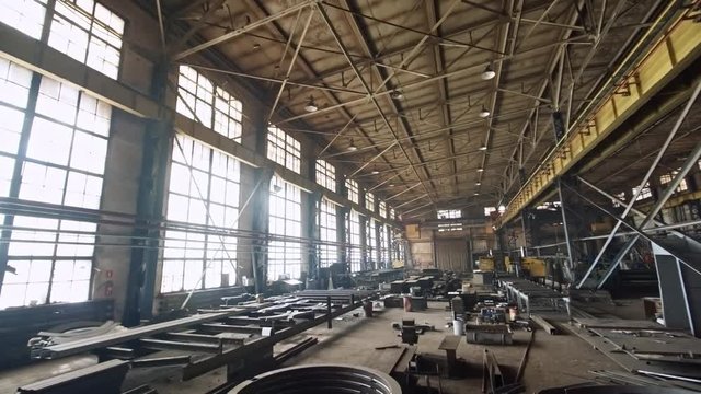 Wide tilt down shot of large steel parts and products lying in metal fabrication facility