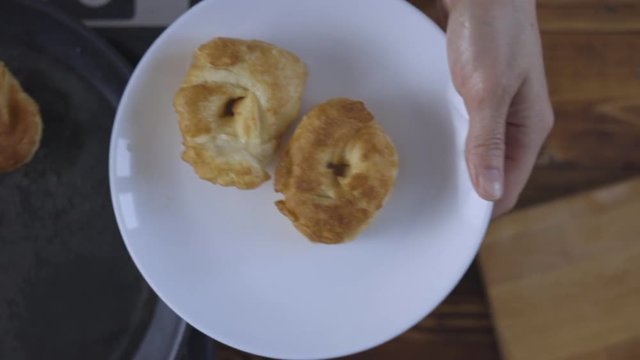 Woman is taking hot pastry from frying pan