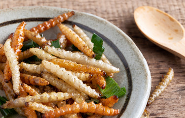 Bamboo edible worm insects crispy or Bamboo Caterpillar in a ceramic bowl on a wood table. The concept of protein food sources from insects. It is a good source of protein, vitamin, and fiber.
