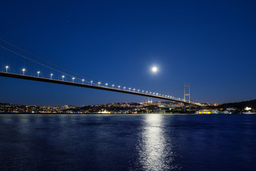 Fototapeta na wymiar Bosphorus Bridge illuminated by lights and moon at night