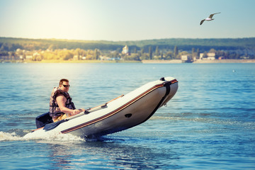 Inflatable white motor boat with driver under bright sun
