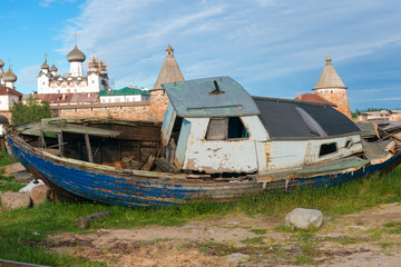 Old fishing boats on the shore against the background of the Transfiguration of the Solovetsky...