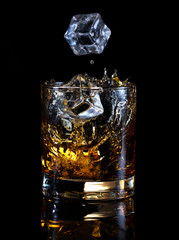 Ice cubes falling in glass of whiskey