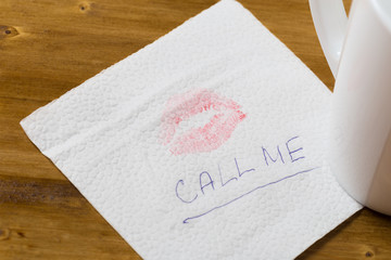 Napkin with a kiss and coffee cup on wooden background.