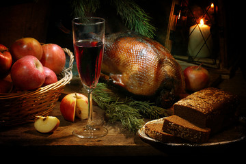 Roasted goose with red wine, apples, with candles, a flashlight and a spruce branch