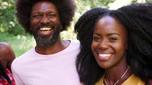 Four black adult friends smile to camera in a forest, close up