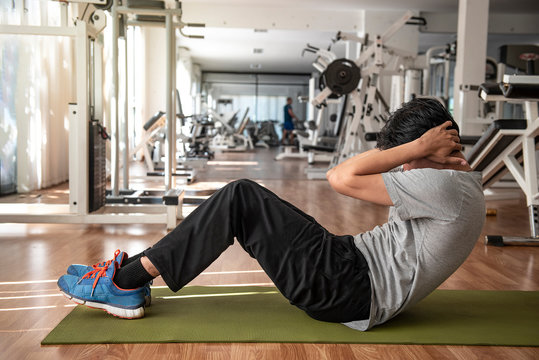 Full length of young   athletic  man in sportswear doing push-up  muscular exercising on green mat in fitness gym. - Image