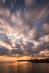 Beautiful wide angle, long exposure view of a lake at sunset, with an huge sky with moving clouds