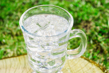 Fresh drink water with ice in glass on nature background
