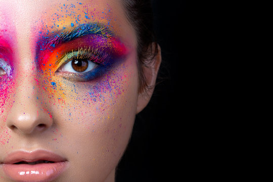 Close up view of female face with bright multicolored fashion makeup. Holi indian color festival inspired. Studio macro shot. Copy space.