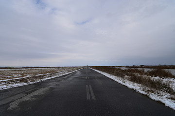 Empty asphalt country road leading to Loudias River delta in a winter day.  Axios-Loudias-Aliakmonas National Park, Greece