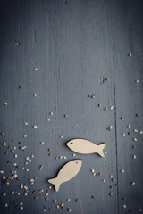 Kommunion, Konfirmation, Firmung, Taufe - Holzfische in beige auf grau blauen Holz mit Kieselsteinen