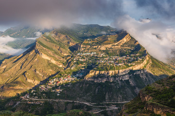 Gunib highland village placed on a mountain plateau in Caucasus Mountains. Natural fortress and popular tourist place. Beautiful sunny landscape in a morning with low clouds. Dagestan Republic, Russia