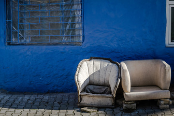 Fototapeta na wymiar Old Sofa Chairs Abondoned in front of a Blue Wall