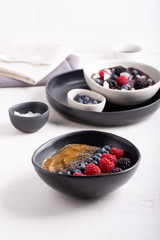 Smoothie bowls on white background. Delicious mango smoothie topped with chia seeds and berries. Berry smoothie topped with coconut flakes and berries (raspberry, blackberry, blueberry).
