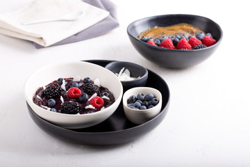 Smoothie bowls on white background. Delicious berry smoothie topped with coconut flakes and berries (raspberry, blackberry, blueberry). Mango smoothie topped with chia seeds and berries.