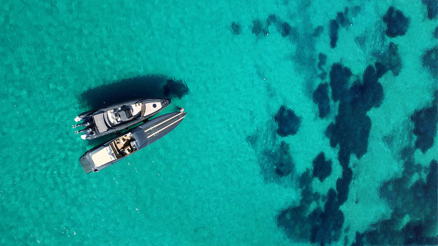 Aerial drone photo of speedboats docked in popular beach of Paradise, Mykonos island, Cyclades, Greece
