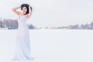 Arabic sexy woman in bright white chiffon long dress at snowy field. Evening fashionable dress, modern romantic bride ,winter fairytale 