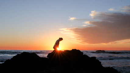 Silhouette of a woman with sunset and cloudy sky as a background