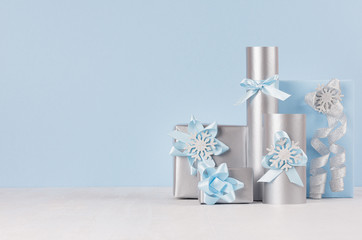Preparation for christmas celebration - blue gift boxes with silver ribbons and glitter snowflakes on white wood table.