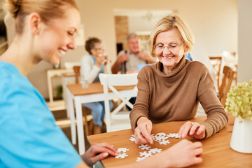 Senior Frau und Pflegedienst beim Puzzle spielen