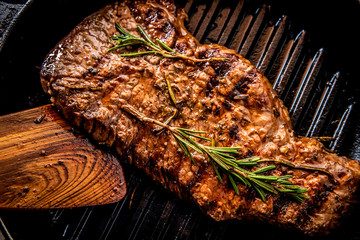 Juicy beef steak with rosemary on a grill pan.
