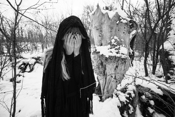 Depressed and lonely woman covering her face in forest in winter.