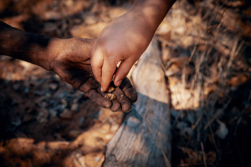 Close Up - Ju/'Hoansi-San Buschmann gibt einem weißen Kind geröstete Mongongo-Nüsse, Grashoek, Namibia