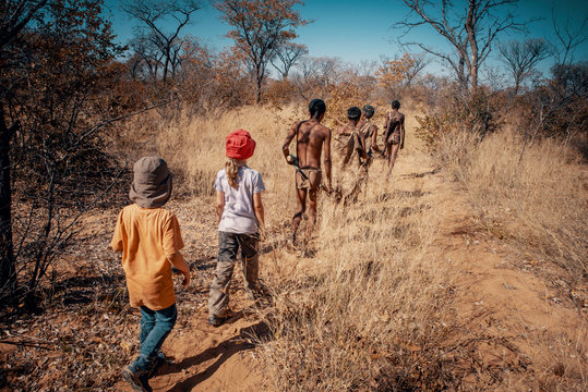 Kinder folgen einer Gruppe Buschm&auml;nner (Ju/'Hoansi-San) durch den Busch, Grashoek, Namibia