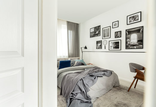 Gallery of photos in white bedroom interior with chair next to bed with grey sheets. Real photo