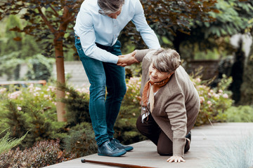 Elder woman getting up with the help of her son