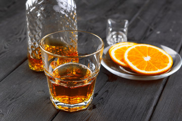 Whisky glass with orange fruit cut on dark wooden background