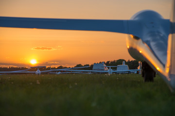 Segelflugzeuge stehen auf einem Flugfeld im Sonnenuntergang