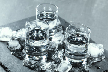 Cold vodka in shot glasses on a black background.
