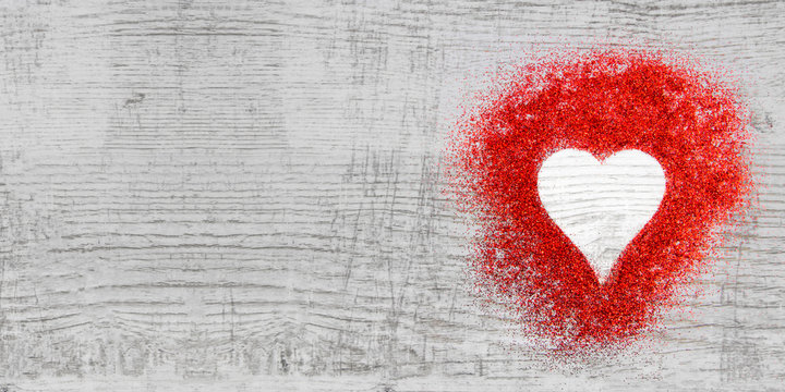 Heart shaped red sparkles on wooden background