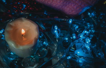 Burning candle on a background of blue lights
