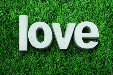 Love made from concrete alphabet top view on green grass