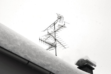 Snow on roof after two days of snowfalls. Television antenna covered with snow. Black and white...