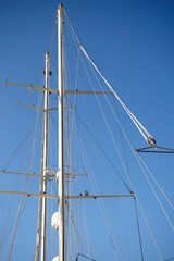 Mast of a sailing yacht and rigging against the background of a clear blue sky.