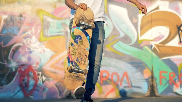 Male teenager is lifting a skateboard with his leg