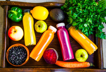 Healthy lifestyle concept with juice bottles, vegetables and fruits on wooden tray, top view, healthy living fitness concept