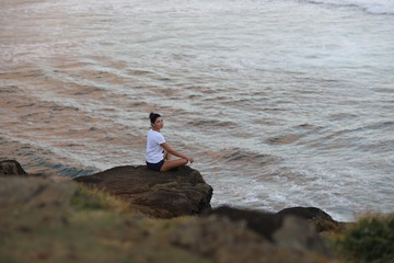 Girl posing sitting on a stone cliff