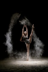 Obraz na płótnie Canvas Gorgeous brunette dancing in dust in the dark