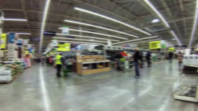 A crowd of buyers walk around the big supermarket of building and finishing materials. Defocused image.