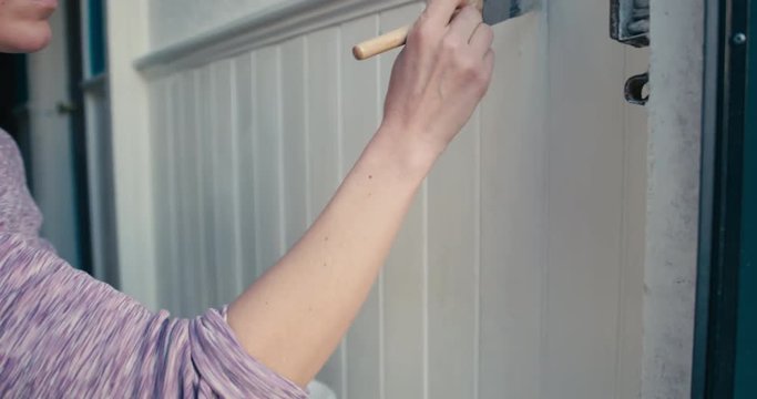 Woman painting cladding in hallway