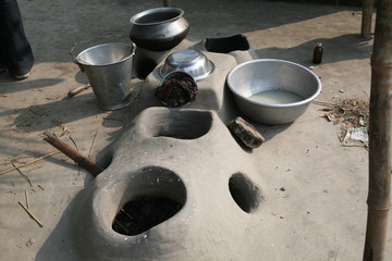 Mud kitchen stove in village outside home. Remnants of firewood, ashes and matches. The pot will be set on top of the round opening, Kumrokhali, West Bengal, India.