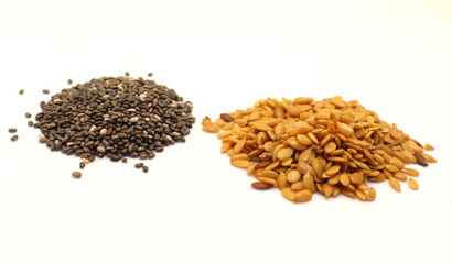 Linseeds and chia seeds, in piles, isolated against a white background